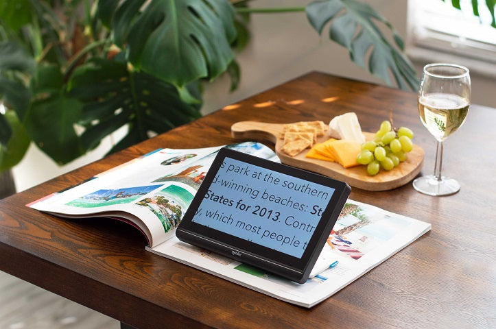 Compact 8 being used to read a magazine. Glass of wine and cheese board in the background